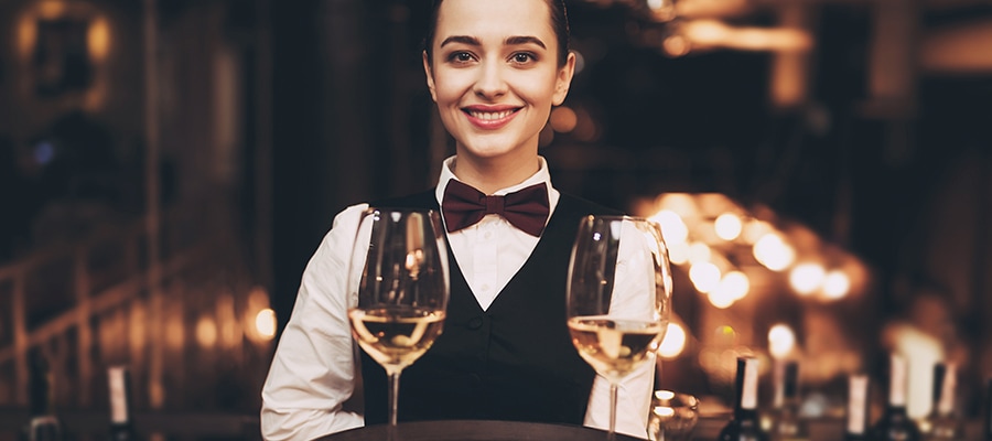 A waitress holding a tray with glasses of white wine and meets customers expectations