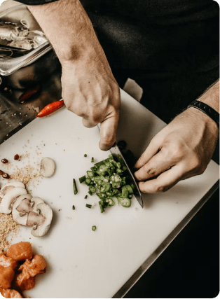 A chefs hands dicing mushrooms on a cutting board