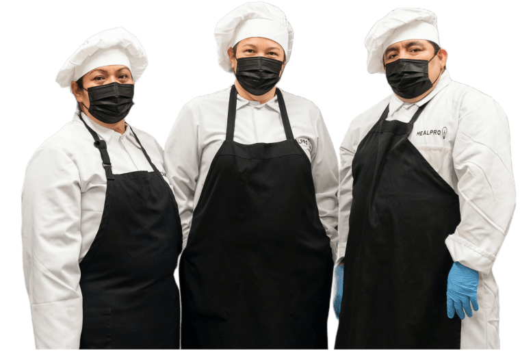 3 happy chefs wearing masks in full cooking attire including white chef hats, black aprons and white chef coats and black masks